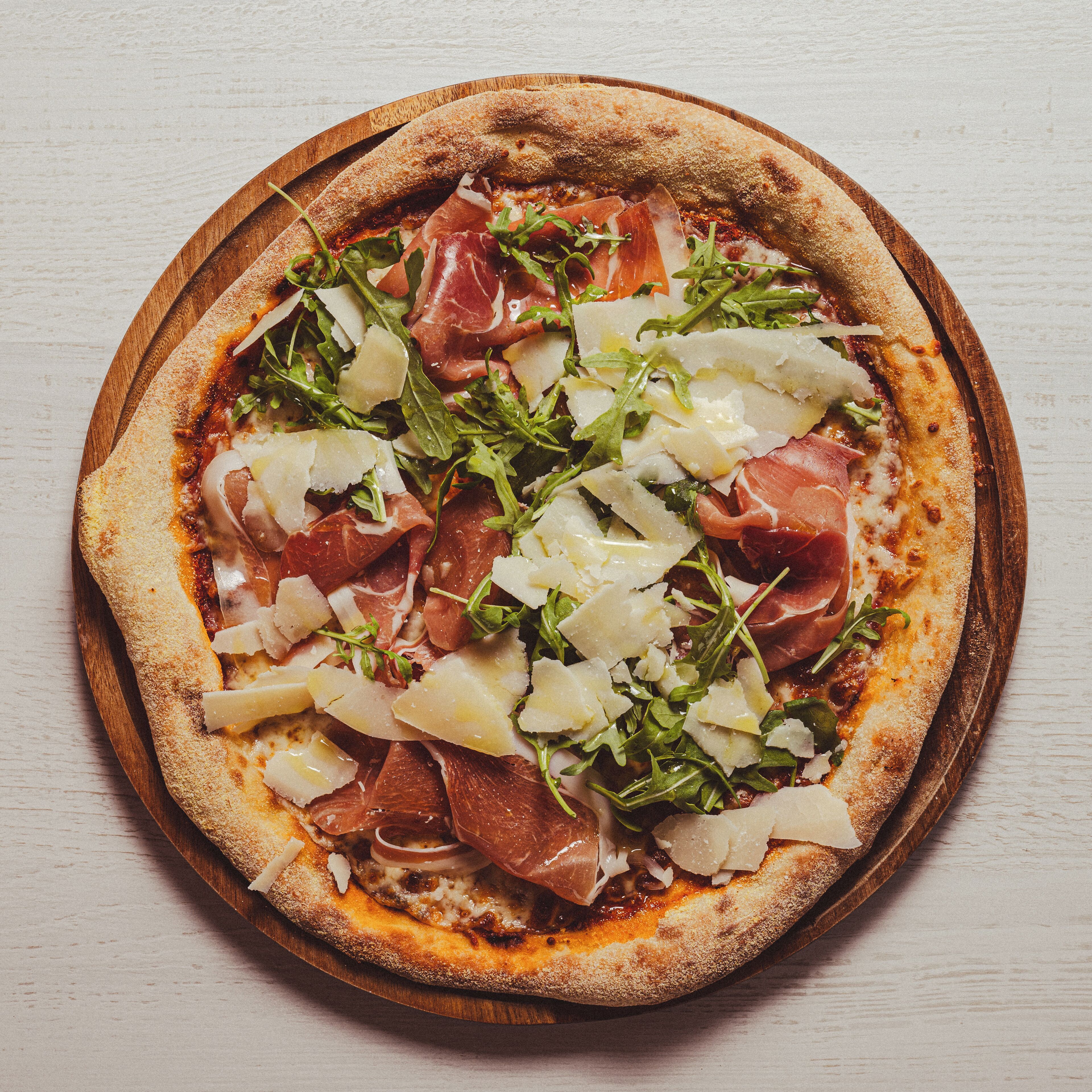 Una pizza con diferentes ingredientes sobre una tabla de madera.