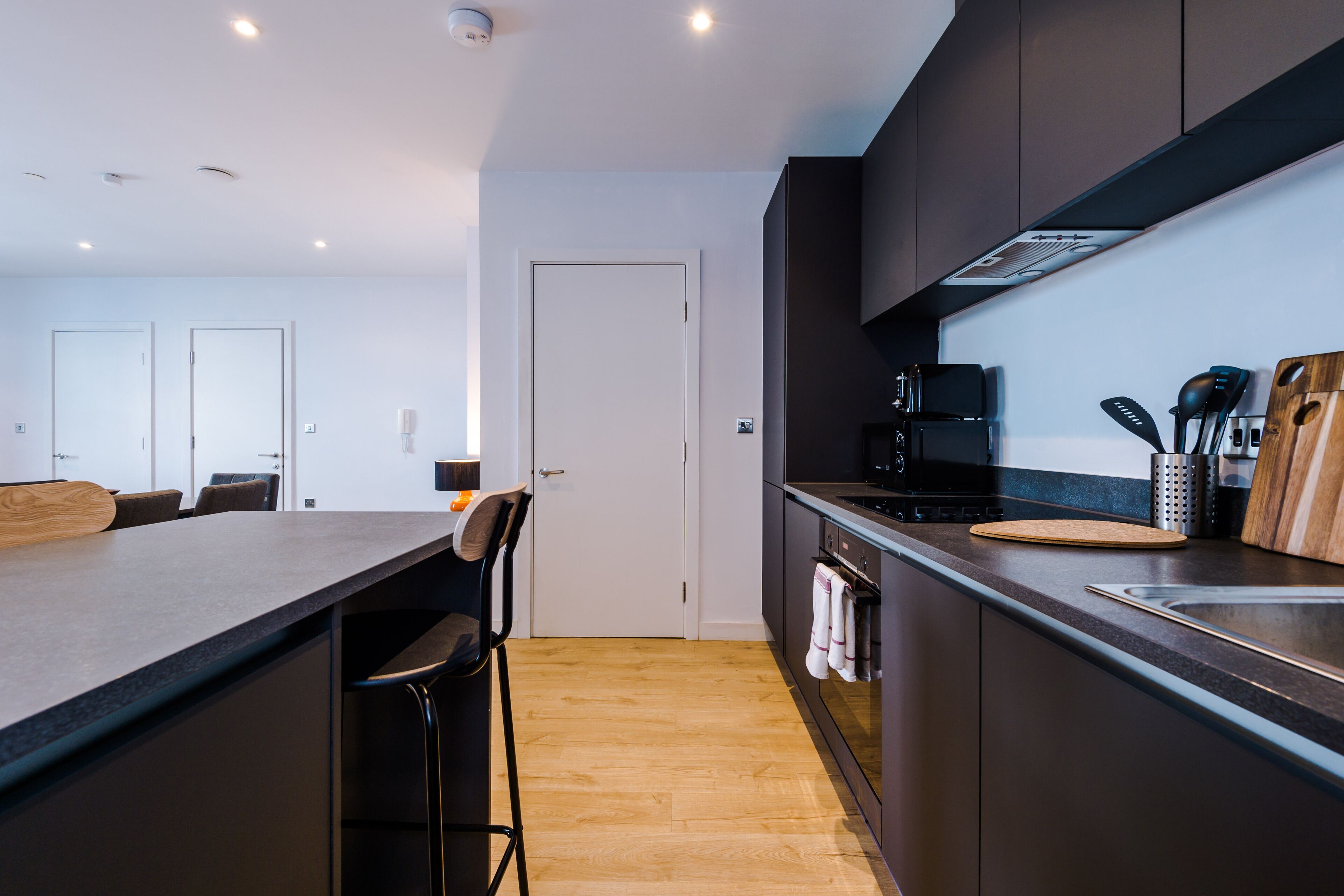 Une cuisine moderne avec des meubles de couleur sombre, un îlot central en bois et un four encastré.
