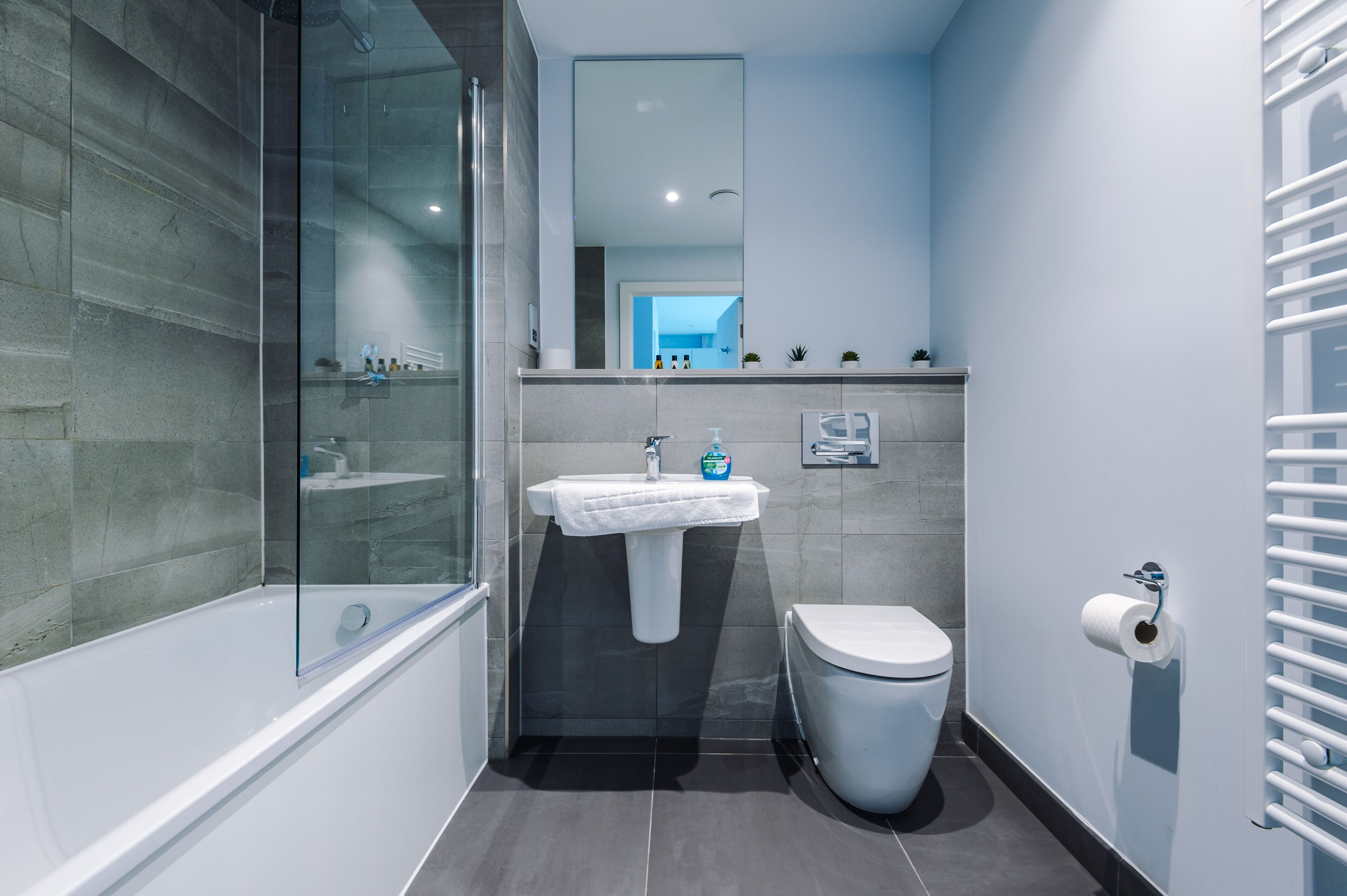 Un bagno moderno con cabina doccia in vetro, lavandino bianco e servizi igienici.