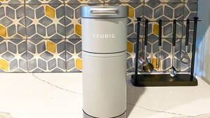 A KEURIG travel mug on a marble countertop with a kitchen utensil holder in the background. - The Lofts at Paso Market Walk - The Elderberry Room (Paso Robles)