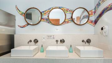 A bathroom with three sinks, a mirror, and a sign instructing to remove personal items.