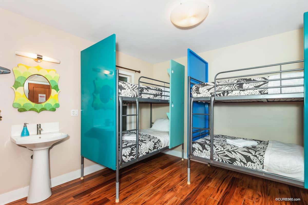 Een kamer met stapelbedden, een wastafel en een spiegel.