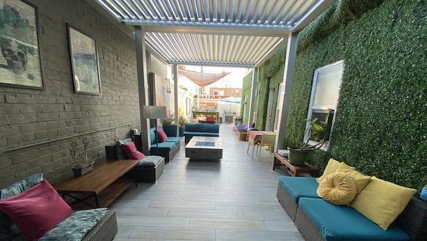 An outdoor patio area with seating arrangements, a pergola, and a green wall. - Samesun Ocean Beach - Hostel (San Diego)