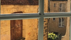 A view through a window of a building with a brick roof and stone walls.