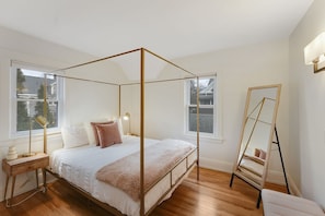 Une chambre à coucher avec un lit à baldaquin, un plancher en bois et de grandes fenêtres.
