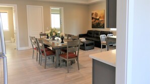Uma sala de estar moderna com um sofá de couro preto, uma mesa de jantar com cadeiras e uma área de cozinha.