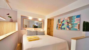 A bedroom with a large bed, a mirror, and a colorful abstract painting on the wall.