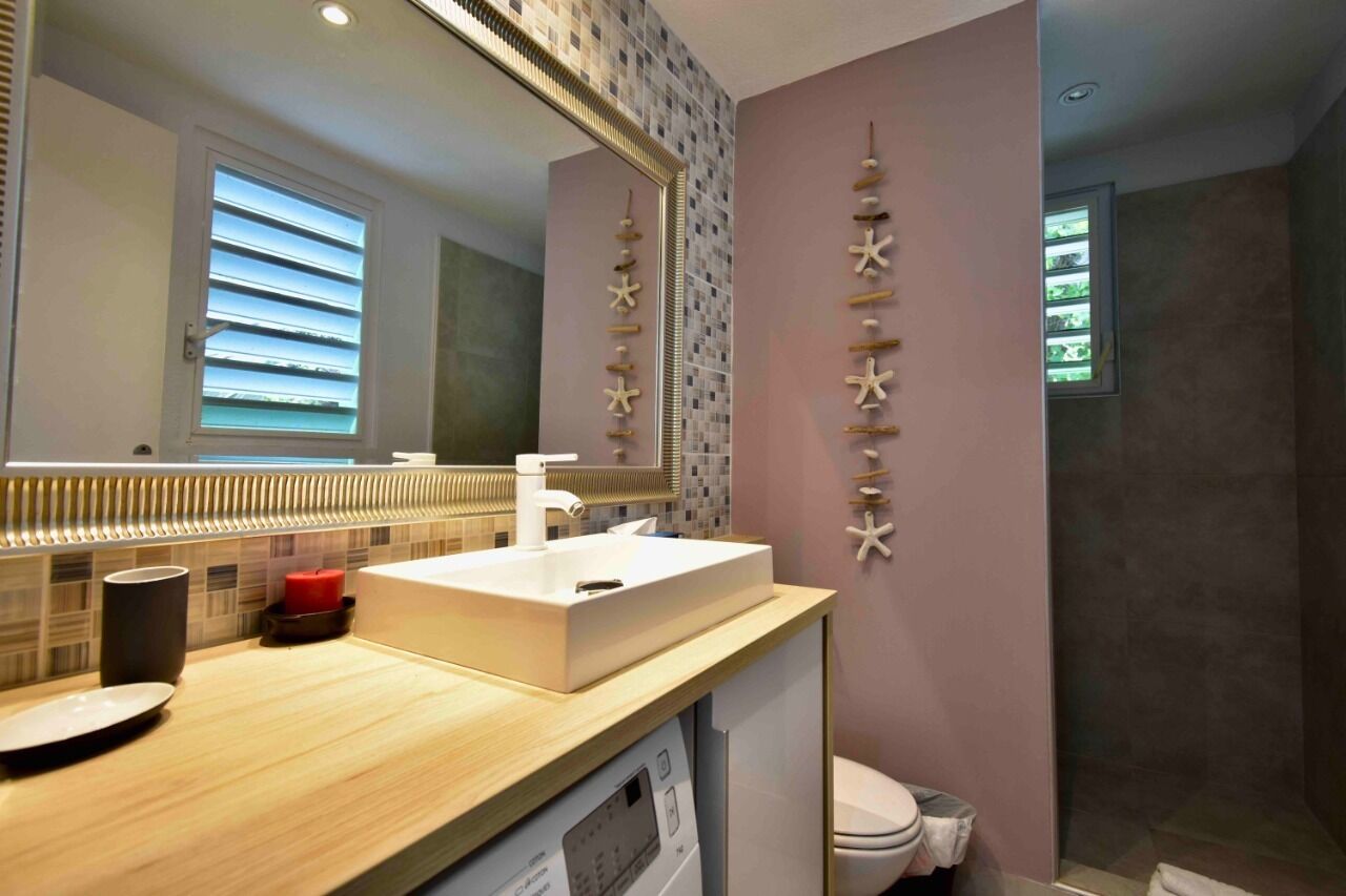 Une salle de bain moderne avec un grand miroir, un lavabo blanc et des toilettes.
