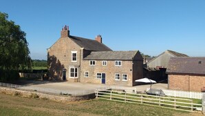 A two-story stone building with a central door and windows, surrounded by a white fence and a grassy area. - Burton Grange Farmhouse B&B (York)