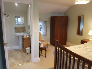 Een slaapkamer met een houten bed, nachtkastje, spiegel en een kledingkast.