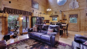 A cozy cabin interior with a leather sofa, wooden floors, and a dining area. - AMAZING GATED COMMUNITY - YOUR OWN PRIVATE SAUNA & HOT TUB ON BACK PORCH (Sevierville)