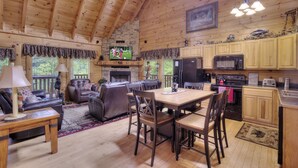 A spacious living area with a fireplace, a television, and a dining table with chairs. - AMAZING GATED COMMUNITY - YOUR OWN PRIVATE SAUNA & HOT TUB ON BACK PORCH (Sevierville)