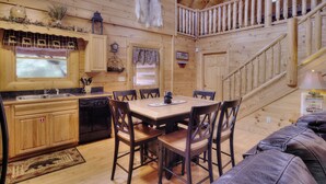 A wooden cabin interior with a dining area, kitchen, and a staircase. - AMAZING GATED COMMUNITY - YOUR OWN PRIVATE SAUNA & HOT TUB ON BACK PORCH (Sevierville)