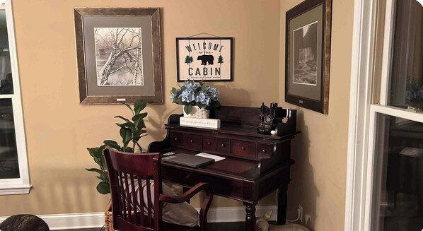 A room with a desk, a chair, a framed welcome sign, and a framed picture on the wall. - Base Camp One! Hot Tub Pool Table Pet Friendly (Cherry Log)