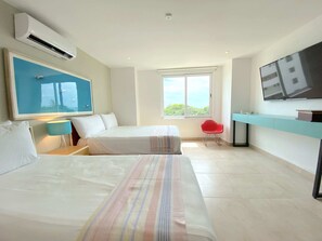 Relax in a spacious room with a large bed, a smaller bed, and a desk for work.