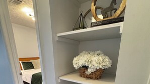 Un corridoio con uno scaffale bianco che contiene libri, un orologio e un oggetto decorativo.