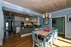 A spacious kitchen with wooden cabinets, a central island, and pendant lighting.