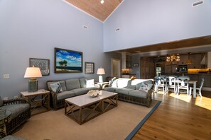 A spacious living room with a large sofa, a coffee table, and a dining area with chairs and a table.
