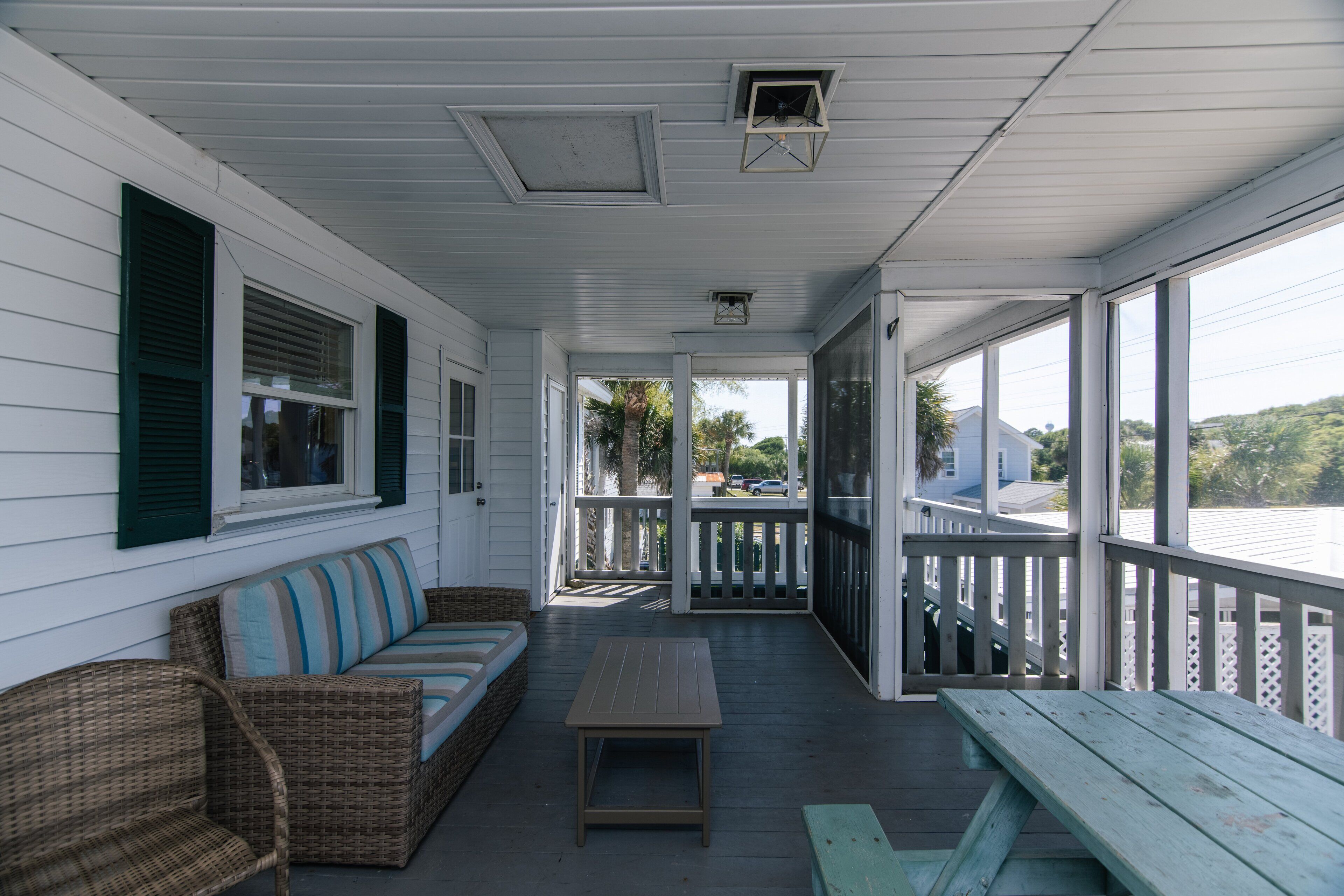 A covered porch with a bench, a table, and a wicker sofa.