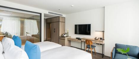 A modern hotel room with a large bed, a desk, a TV, and a seating area.