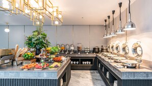 A modern kitchen with a central island, various food stations, and a decorative plant.