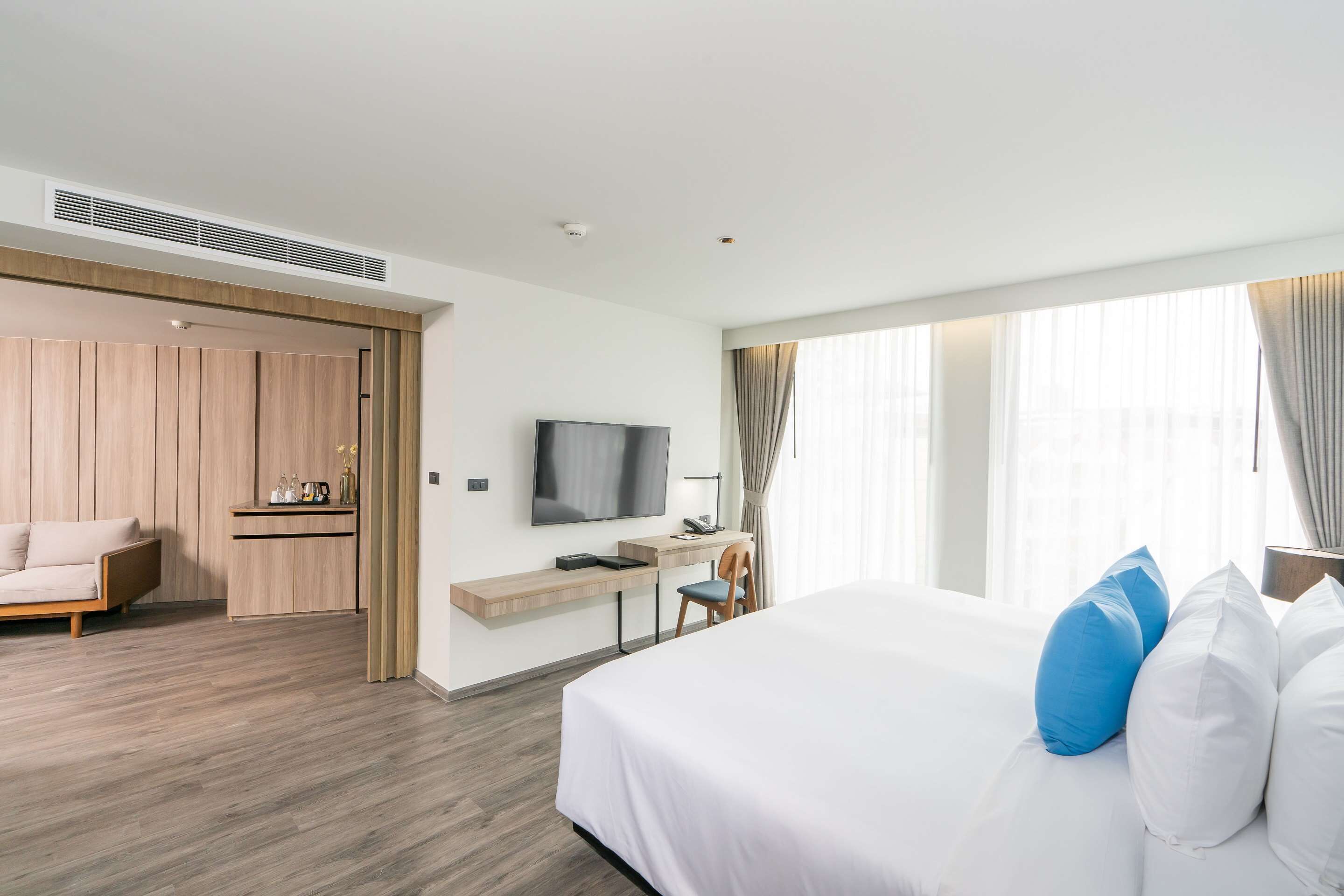 Een moderne hotelkamer met een groot bed, een bureau met stoel, een aan de muur bevestigde televisie en een kledingkast.