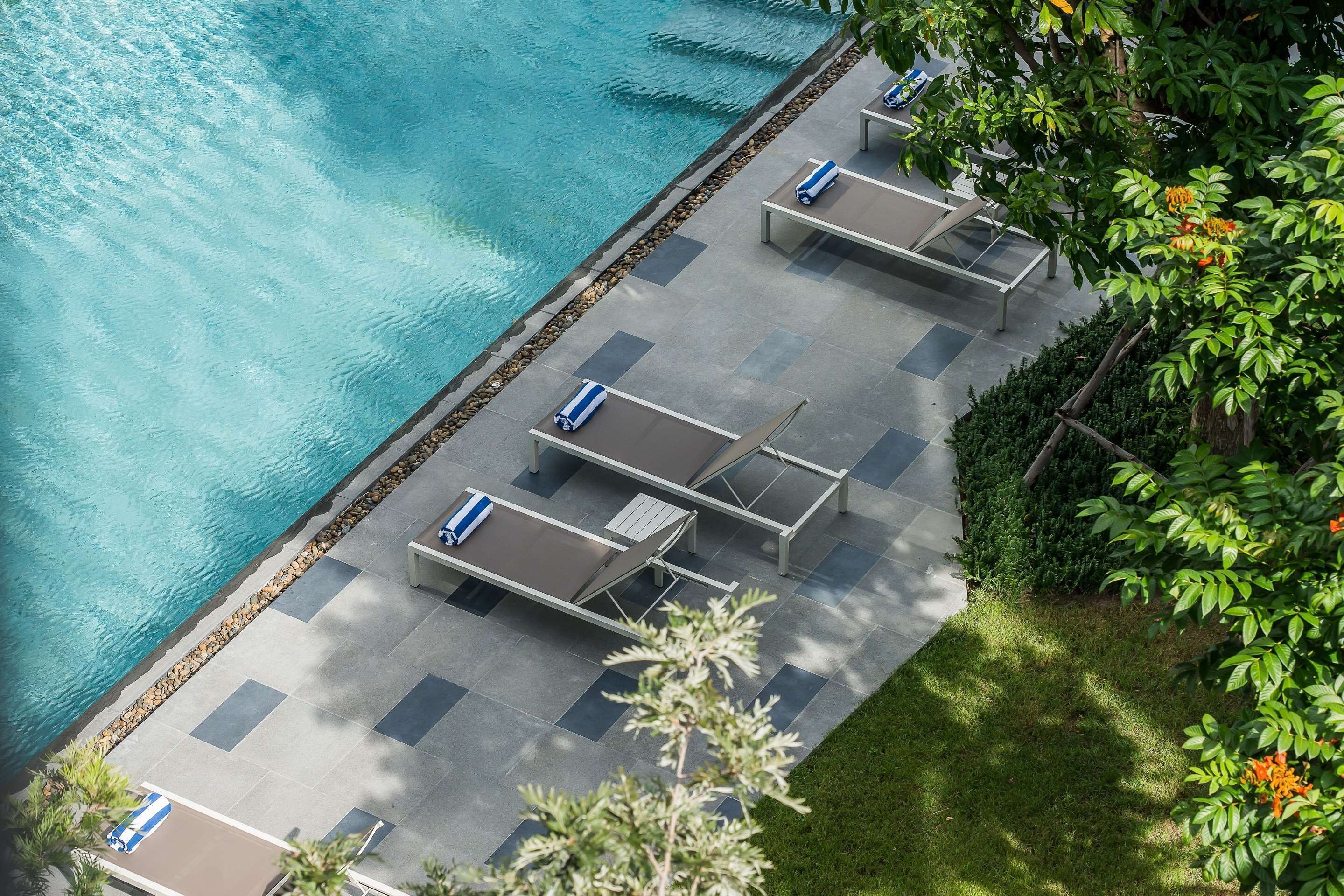 An aerial view of a poolside area with lounge chairs and a tiled deck.