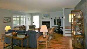 A living room with a sofa, two lamps, a television, and a bookshelf.