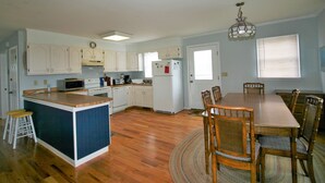 A spacious kitchen with wooden cabinets, a central island, and a dining area with a table and chairs.