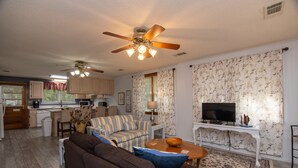 A compact living space with a kitchenette, a sofa, a television, and a ceiling fan. - Pet Friendly Cottage w/ Screened Porch & Easy Beach Access: WiFi Access (Edisto Beach)