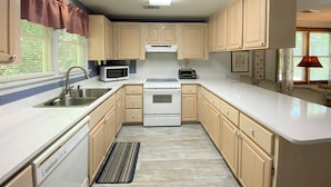 A kitchen with beige cabinets, a white stove, a microwave, a toaster, and a sink. - Pet Friendly Cottage w/ Screened Porch & Easy Beach Access: WiFi Access (Edisto Beach)