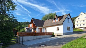 A two-story house with a sloped roof, a front porch, and a small garden area. - Ferienhaus Rudenberg (Titisee-Neustadt)