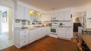 A modern kitchen with white cabinets, a microwave, an oven, and a wooden dining table.