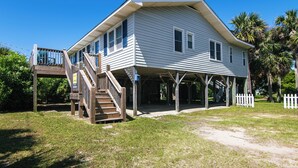 A two-story house with a covered porch and a wooden staircase leading to a deck.