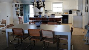 A modern kitchen with a central island, white cabinetry, and a dining area with wicker chairs.