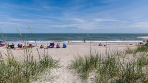 Une plage où l’on voit des gens se détendre sur le sable et d’autres dans l’eau.