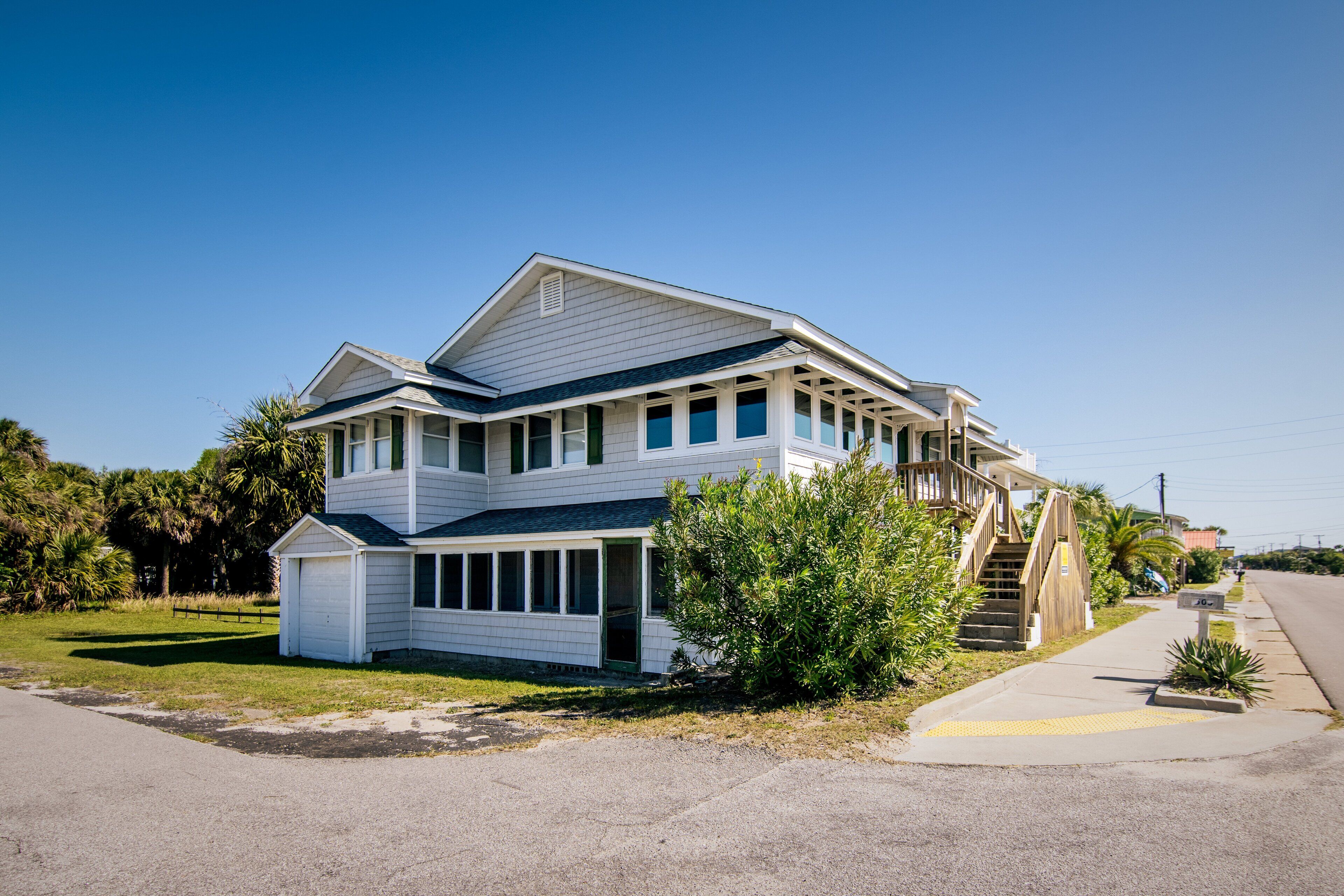 A two-story house with a covered porch, a small attached garage, and a staircase leading to the upper level.