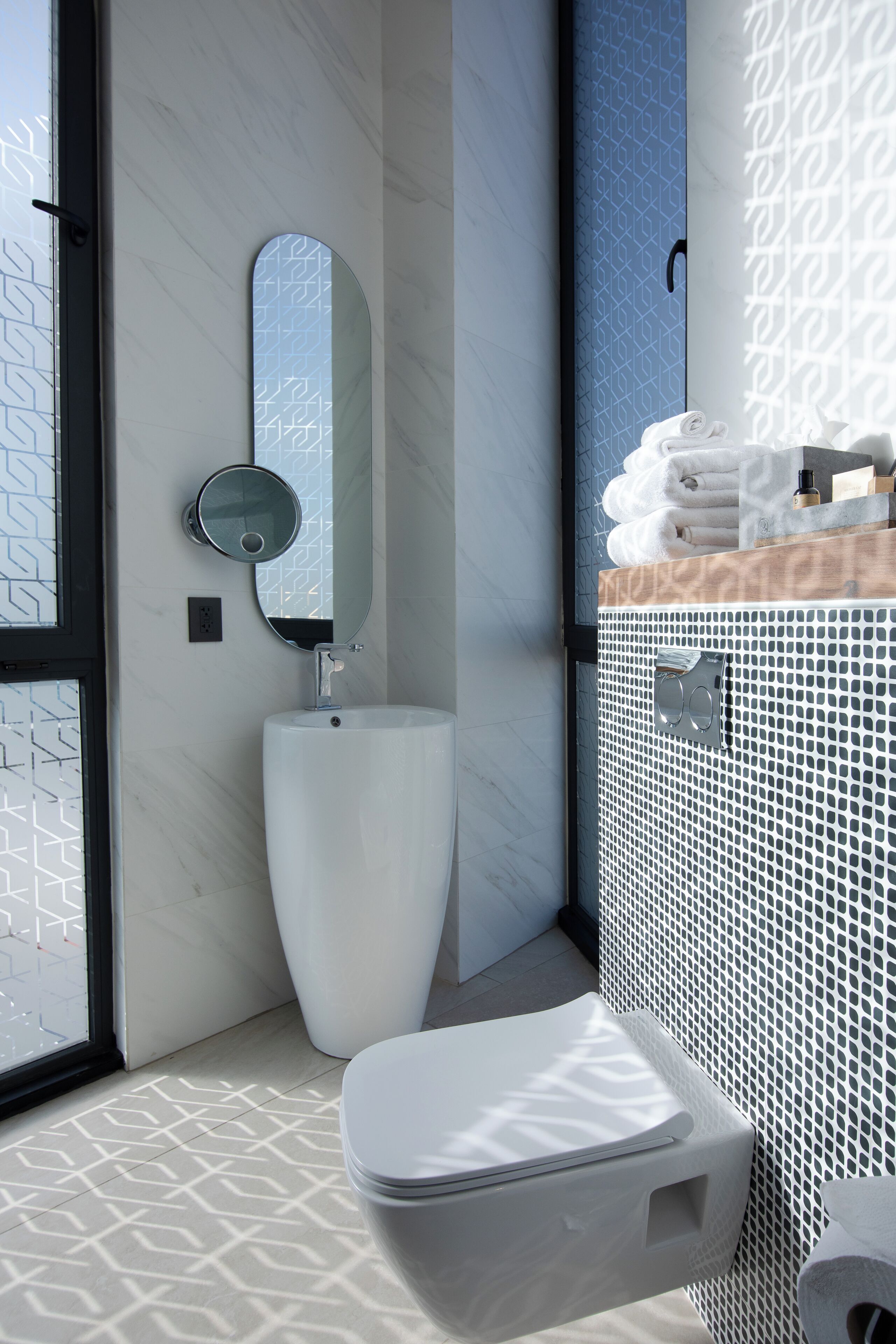 A modern bathroom with a white toilet, a round mirror, and a sink.