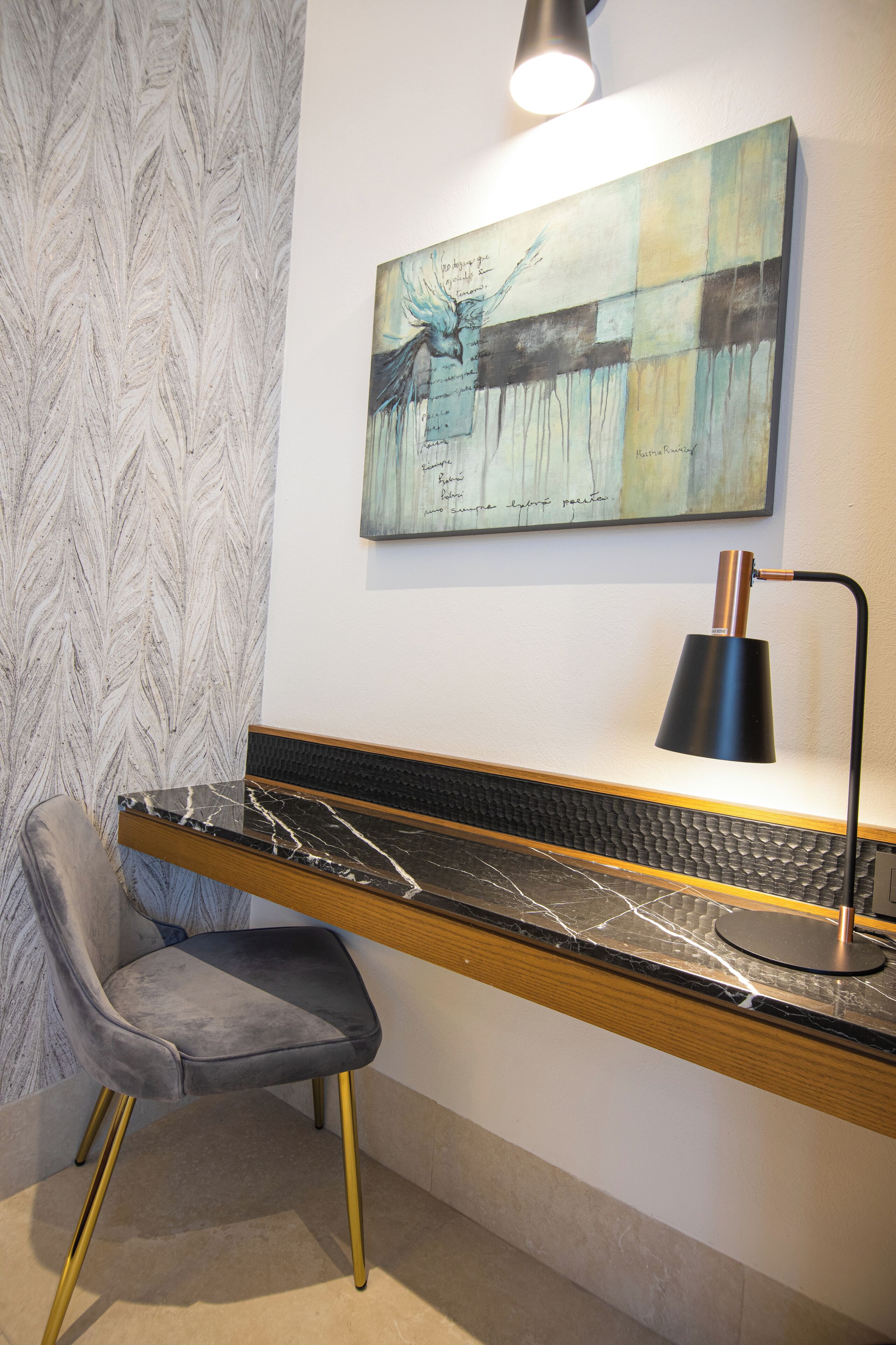 A modern workspace with a marble desk, a black lamp, and a grey chair.