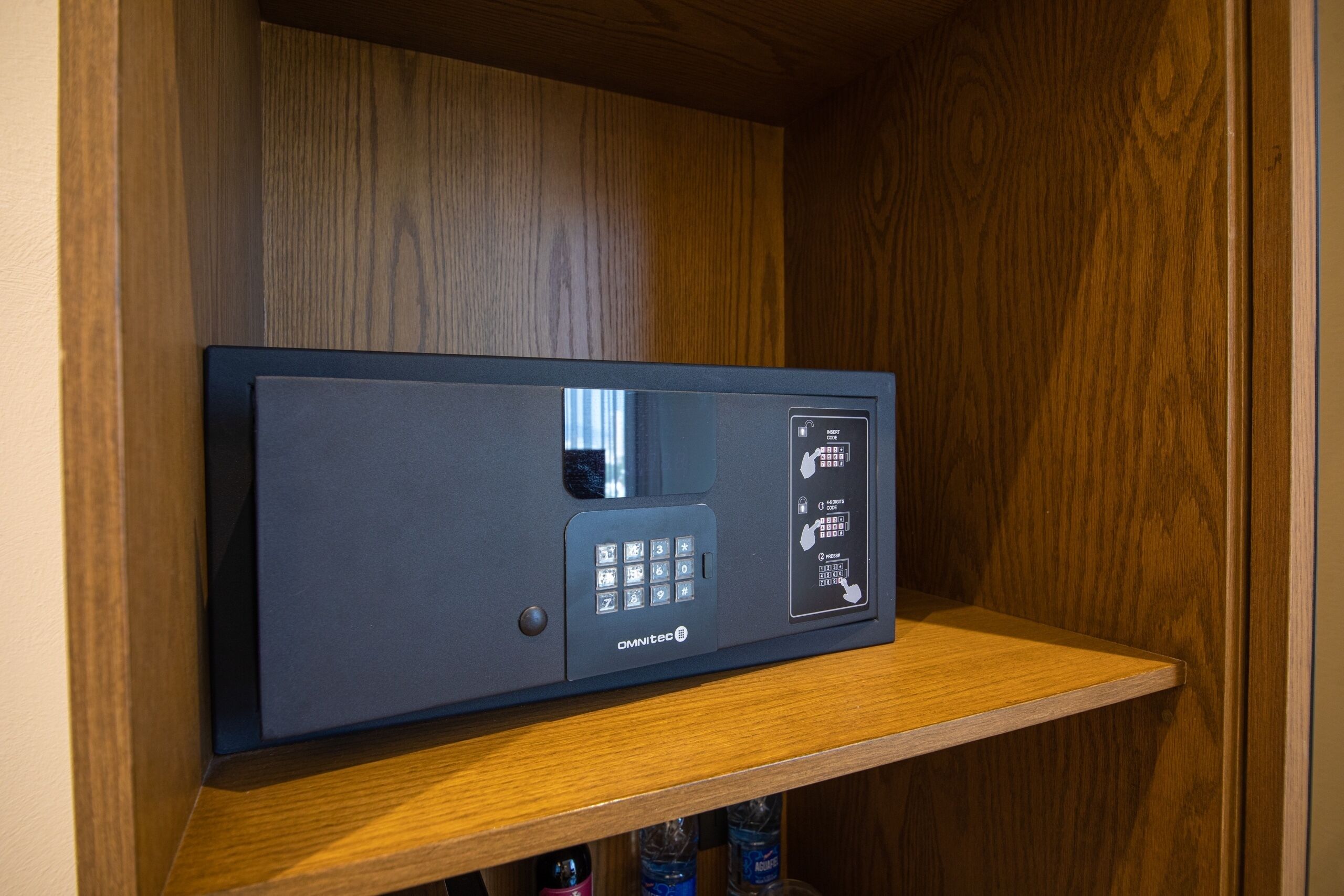 A black security device with a keypad and a small screen, mounted on a wooden shelf.