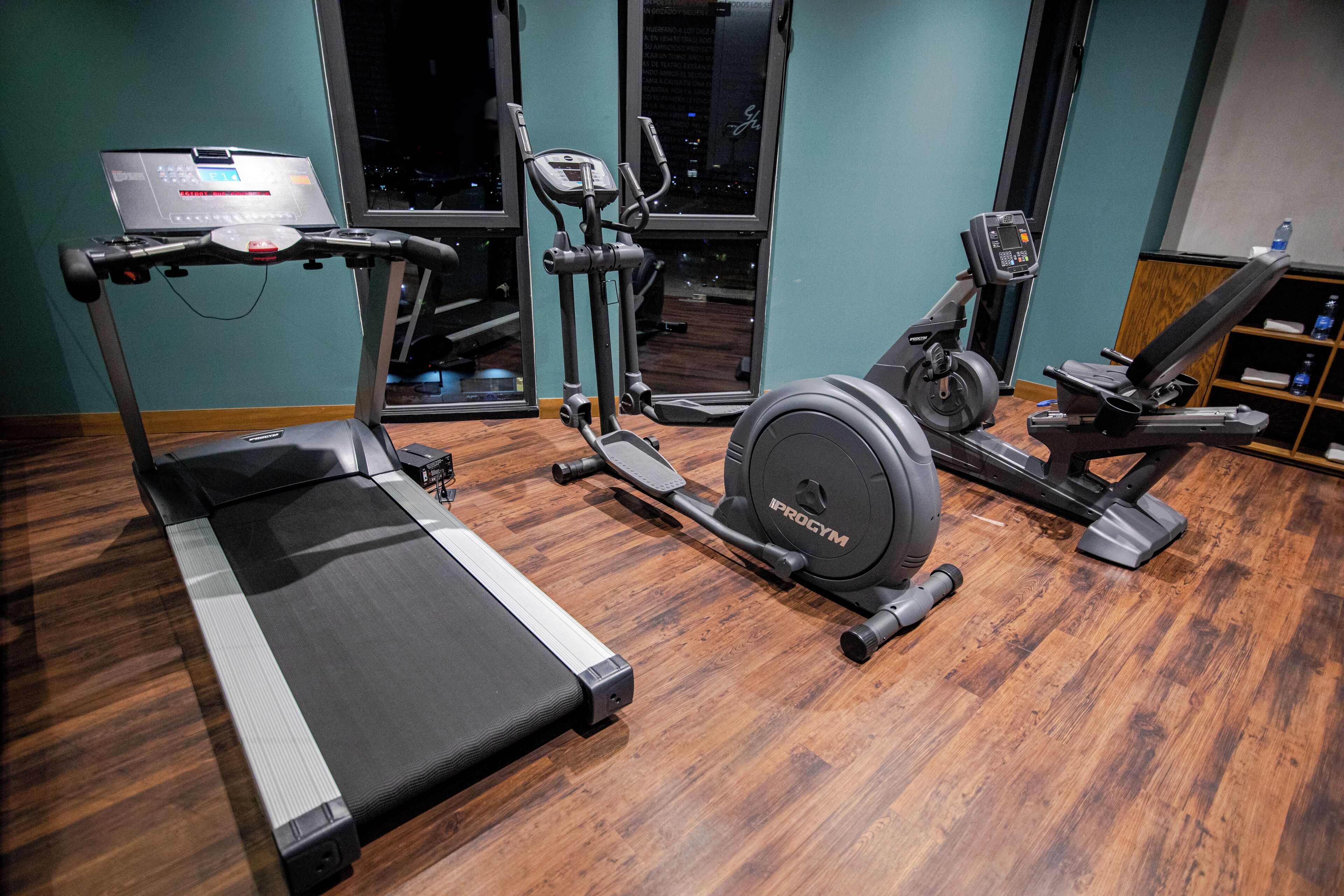 A gym with a treadmill, elliptical, and stationary bike.