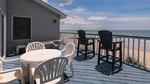 Een terras met tafel en stoelen, met uitzicht op een strand.
