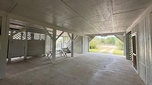 An empty covered patio area with concrete flooring, white wooden beams, and lattice panels. - Second Row Classic w/ Screened Porch; Across the Street From Beach Access; WiFi & Cable TV's (Edisto Beach)