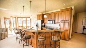 A spacious kitchen with wooden cabinets, a central island with bar stools, and pendant lighting. - Prime Lakefront East Okoboji Condo at Bridges Bay Jet Ski Lift rental available! (Arnolds Park)