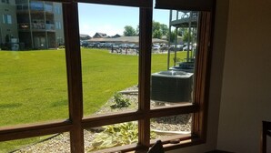A room with large windows overlooking a grassy area and a parking lot. - Prime Lakefront East Okoboji Condo at Bridges Bay Jet Ski Lift rental available! (Arnolds Park)