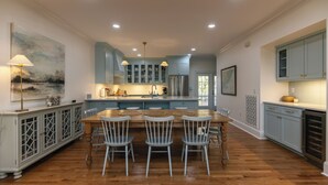 Una cocina amplia con una isla central, piso de madera y armarios azul claro.
