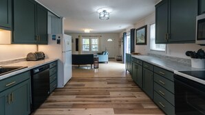 A kitchen with green cabinets, a dishwasher, a microwave, and a toaster. - Villa Kunterbunt | Classic Beach Walk Cottage | Screened Porch & Sun Deck | Sleeps 8 | Pet Friendly (Edisto Beach)