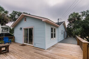 A light blue house with a wooden deck, a sliding glass door, and a blue chair.