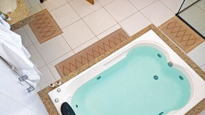 Ein Wellnessbereich mit Whirlpool, Handtuchhalter und Duschbereich.