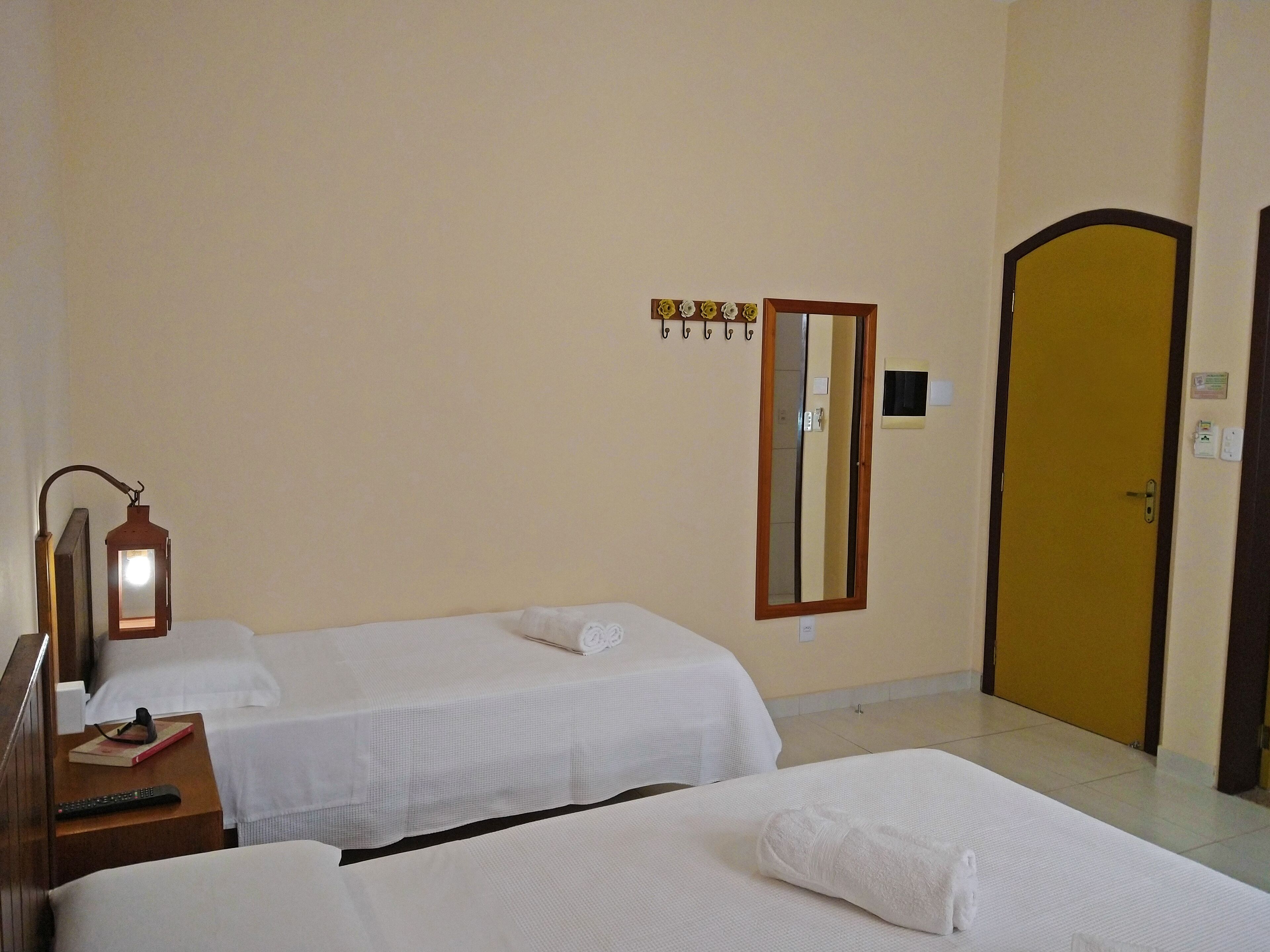 Une chambre d’hôtel avec deux lits, une table de chevet, une lampe, un miroir et une porte.